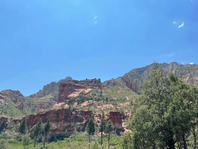 Red rock formations and trees under a clear sky.