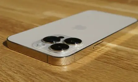 iPhone 13 Pro Max resting face down on a wooden surface.
