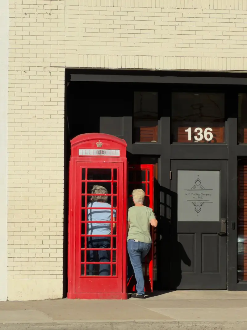 Beside a red telephone booth.